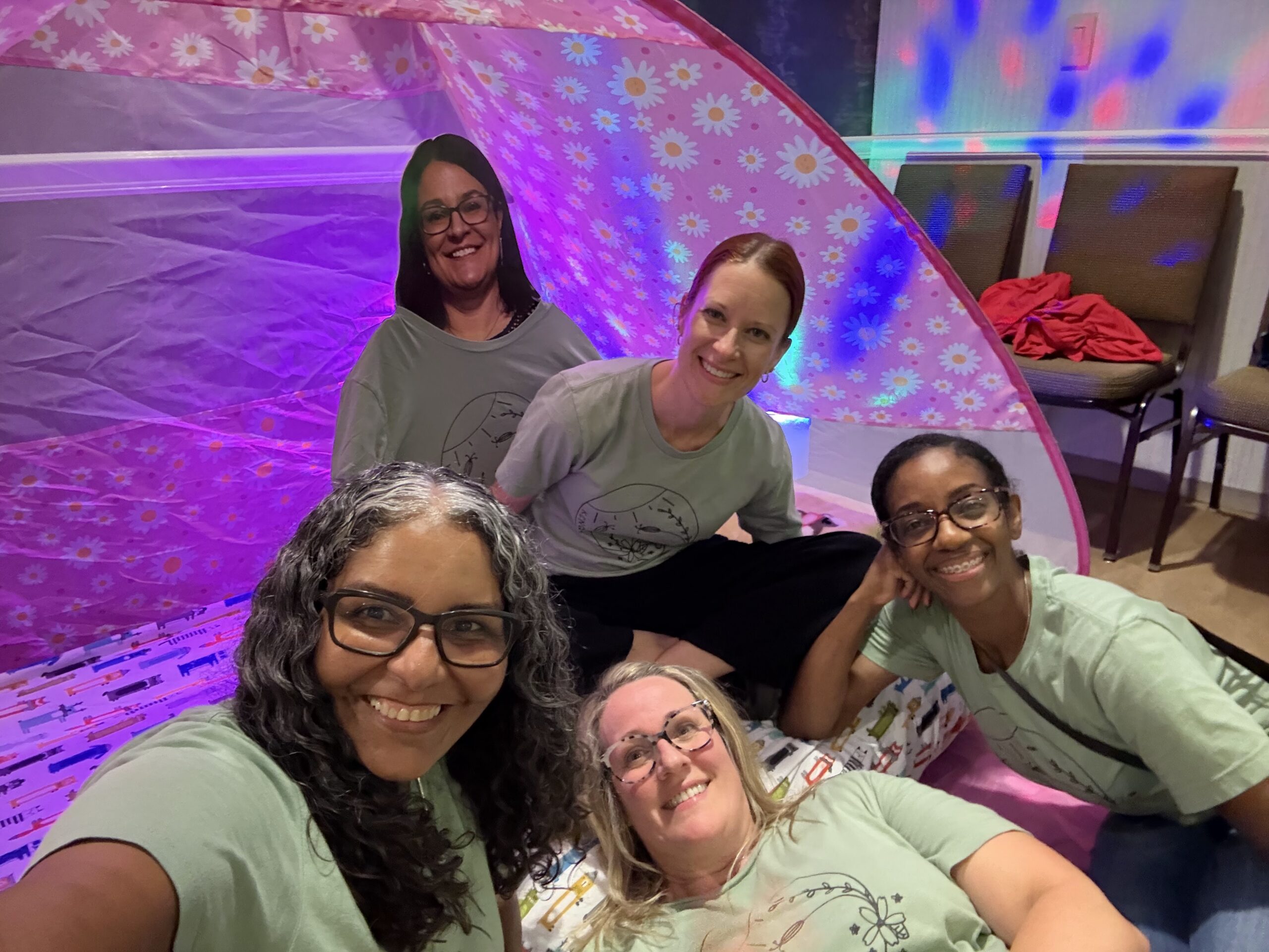 Four KCNQ2 moms smiling together in a sensory tent at the Summit