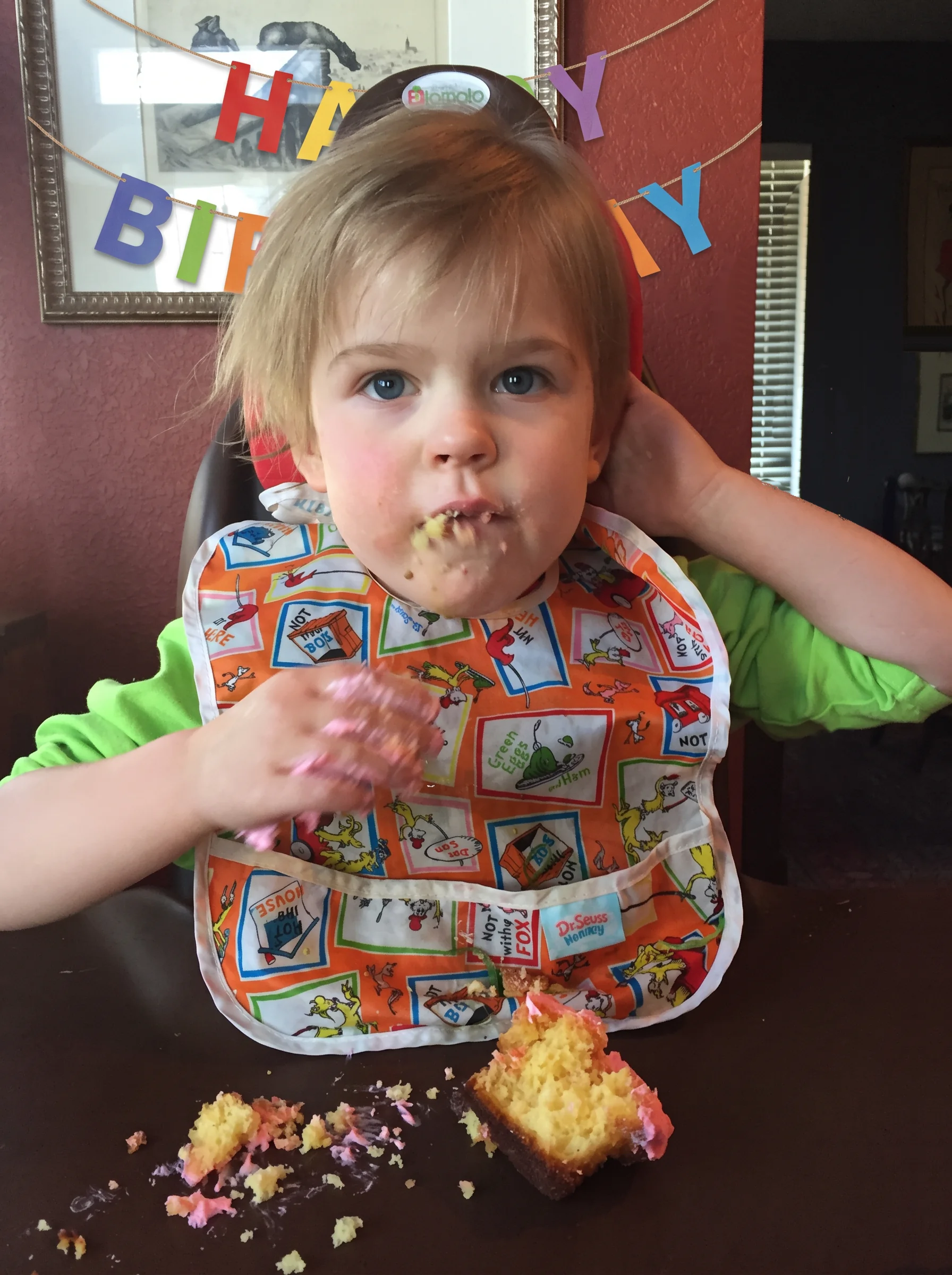 A girl eating a cupcake in front of Happy Birthday letters at a KCNQ2 birthday fundraiser